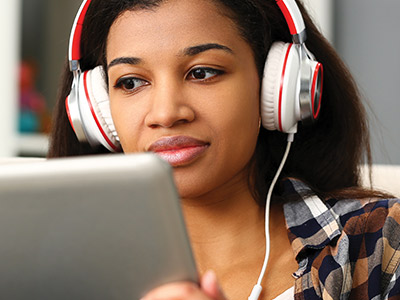 Young woman with headphones looking at computer.