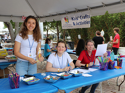 Library volunteers smiling behind a table of crafts.