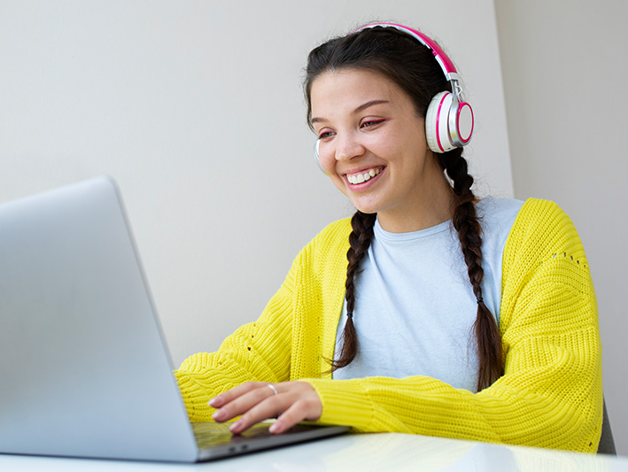 Teenage Girl with headphones looking at laptop computer.